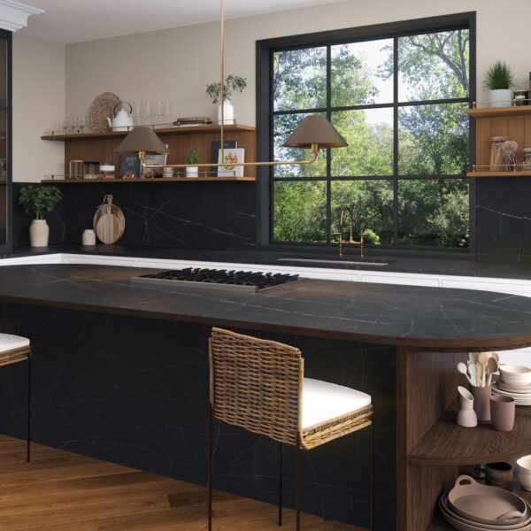 A contemporary kitche with a black oval worktop, rattan chair and decor.