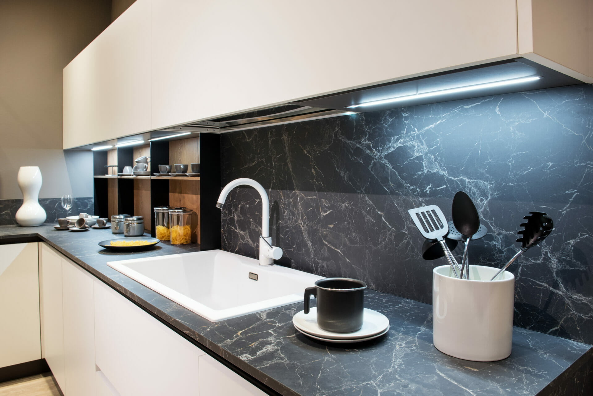 A classic kitchen with black granite kitchen splashbacks and worktops, sink and kitchen utensils.